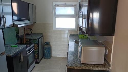 a small kitchen with a stove and a window at شاليه Do1 ثلاث غرف مكيف بالكامل 2حمام للايجار بمطروح قرية لونج ايلند كورنيش روميل "family" in Marsa Matruh