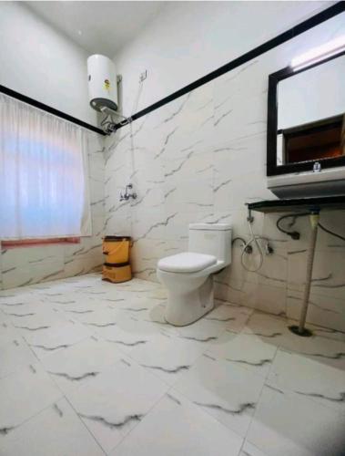 a white bathroom with a toilet and a window at Hotel Janat Heritage in Jaisalmer