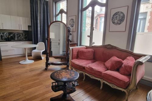 un salon avec un canapé rouge et une table dans l'établissement Maison Verte, Monument Historique, à Roubaix