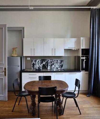 Il comprend une cuisine avec une table et des chaises en bois. dans l'établissement Maison Verte, Monument Historique, à Roubaix