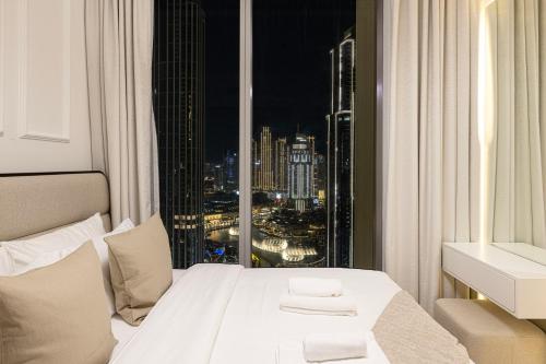 a bedroom with a bed with a view of a city at Luxury 4BR Burj Khalifa & Fountain Views in Dubai
