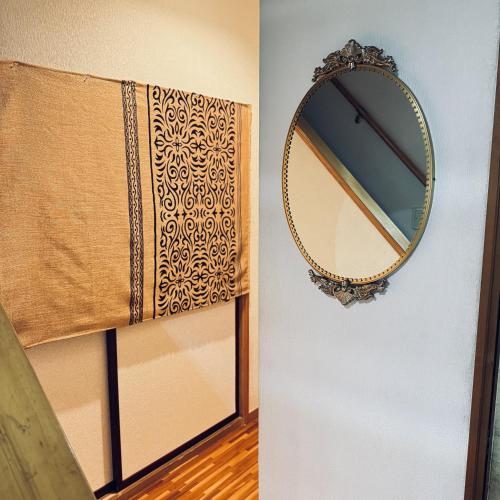 a mirror on a wall next to a window at Thanyaporn House in Takayama