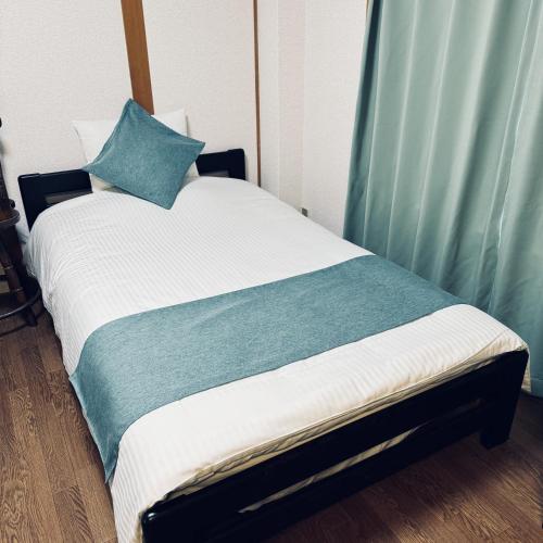 a bed with a blue pillow on top of it at Thanyaporn House in Takayama
