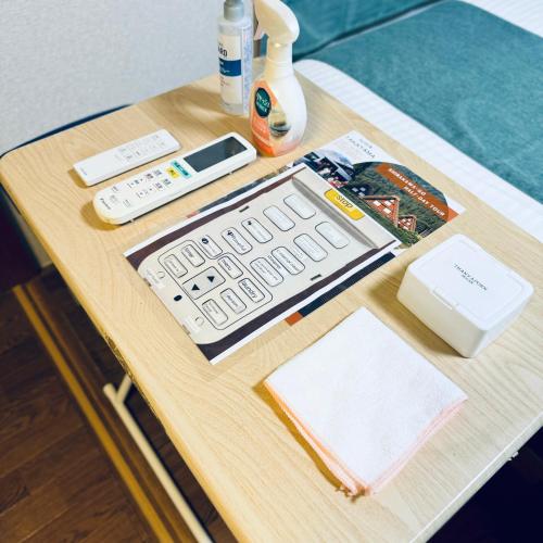 a wooden table with a computer keyboard and remote controls at Thanyaporn House in Takayama