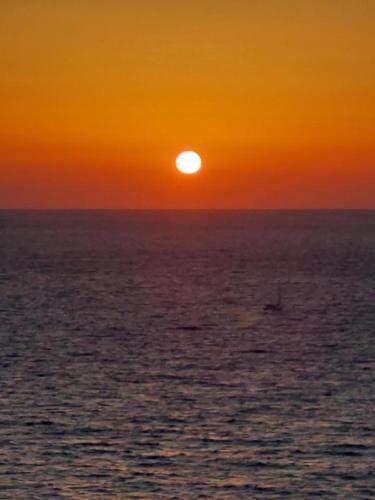 a sunset over the ocean with a boat in the water at Porto Katsiki House in Athanion