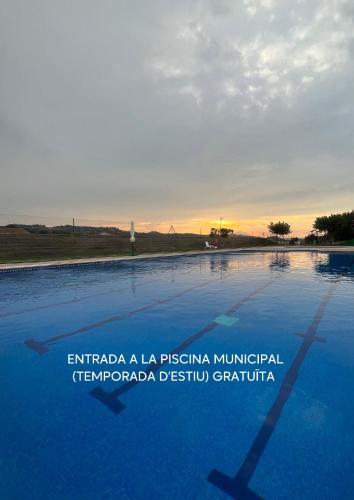 a swimming pool with the sunset in the background at Cal Teca Rural in Sant Antolí i Vilanova