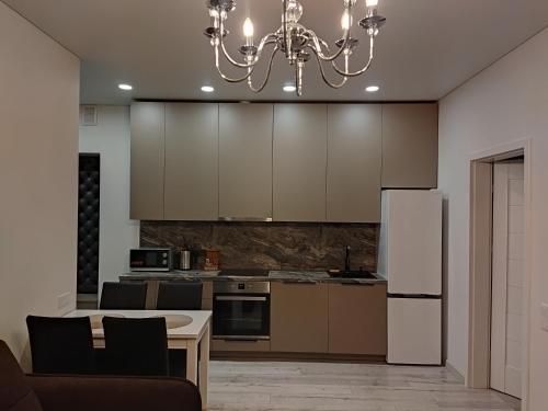 a kitchen with a table and a white refrigerator at Aušros Alėjos Apartamentai in Šiauliai