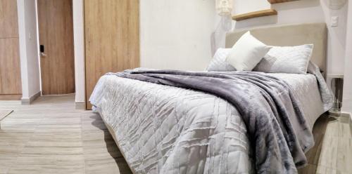 a bedroom with a bed with a gray blanket and pillows at Zentrico Boutique in Pereira