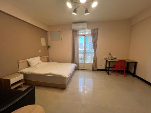 ein Schlafzimmer mit einem Bett, einem Schreibtisch und einem Fenster in der Unterkunft 市區背包客棧-有套房及包棟 in Jincheng