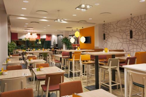 a restaurant with tables and chairs and a wall at Holiday Inn Berlin City East Side by IHG in Berlin