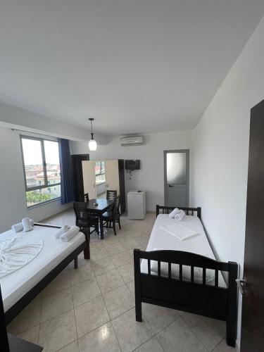 a bedroom with two beds and a table and chairs at Hotel Restaurant Globi in Velipojë