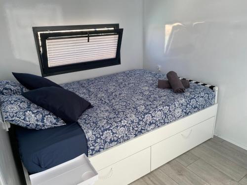 a small bedroom with a bed with blue and white sheets at Houseboat Cádiz El Puerto - Casa Flotante in El Puerto de Santa María