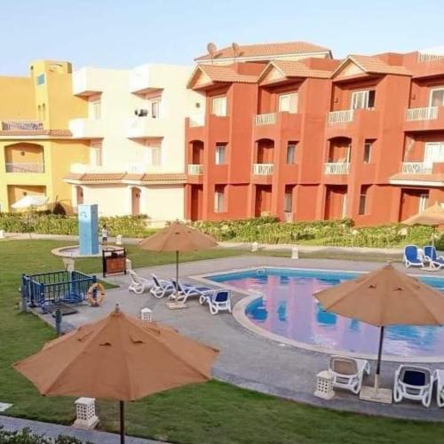 a pool with umbrellas and chairs and a large building at بورتو مطروح in Marsa Matruh