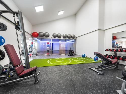 a fitness room with a gym with a green carpet at Steigenberger Hotel Treudelberg Hamburg in Hamburg