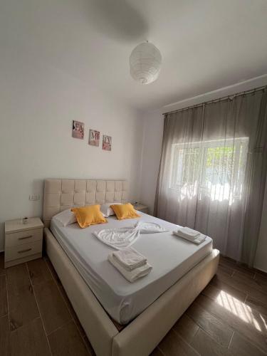 a bedroom with a bed with white sheets and a window at Doris Apartments in Himare