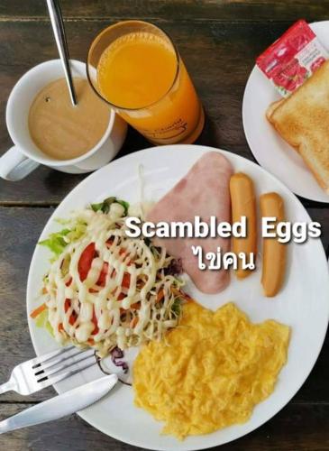 a white plate of food with scrambled eggs and a drink at ลูกช้างเขาใหญ่แคมป์ in Ban Tha Maprang