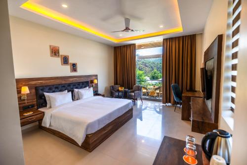 a hotel room with a bed and a television at Aotel by Clarks Inn Palampur in Pālampur