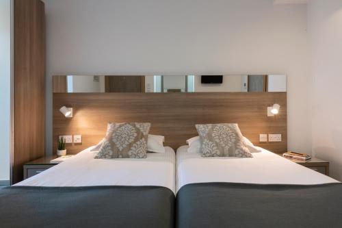 a hotel room with two beds and a mirror at Plaza Regency Hotels in Sliema