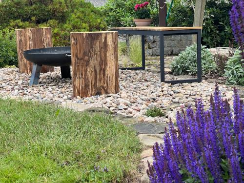 a garden with a bench and a table and flowers at Apartmán Hamerka in Hlinsko