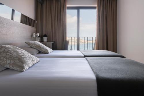 two beds in a hotel room with a large window at Plaza Regency Hotels in Sliema