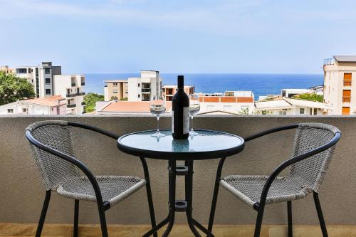 a table with a bottle of wine and two chairs at Apartmani BLUE MOON in Dobra Voda
