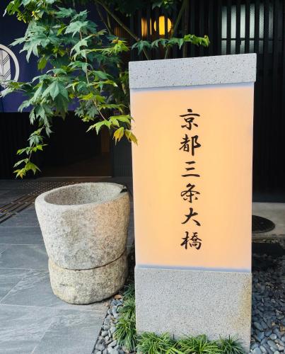an asian sign in front of a plant at Kyoto Sanjo Ohashi in Kyoto