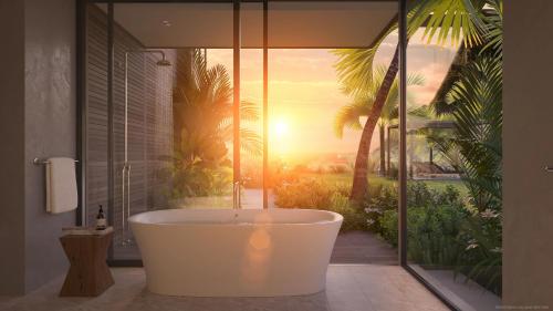 a bath tub in a bathroom with a sunset at Sugar Beach, A Viceroy Resort in Soufrière