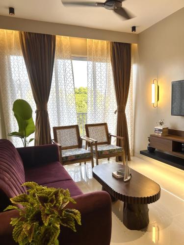 a living room with a couch and chairs and a tv at Elegant 2BHK at Tata Rio De Goa in Vasco Da Gama