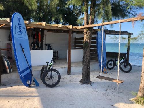a surfboard and two bikes parked on the beach at AVO Boutique Hotel in Dikoni