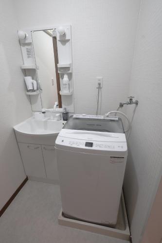 a white bathroom with a sink and a mirror at LN20 NEW KOBE VILLA JR神戸駅徒歩7分!ペット可!最大16名宿泊可能な一軒家a in Kobe