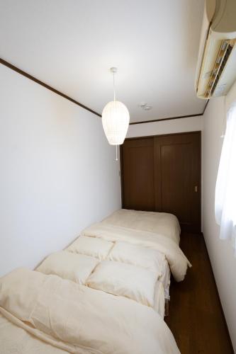two beds in a room with white walls at LN20 NEW KOBE VILLA JR神戸駅徒歩7分!ペット可!最大16名宿泊可能な一軒家a in Kobe