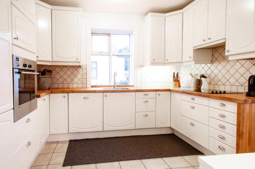 cocina blanca con armarios blancos y ventana en Akureyri Central House, en Akureyri