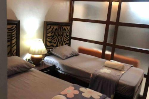 a hotel room with two beds and a lamp at COMFY 1-BR Condo near SLEC, US Embassy, Malls,Park in Manila