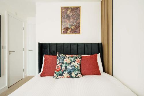 a bed with a black headboard and red pillows at Superb 4BR New House in Leeds