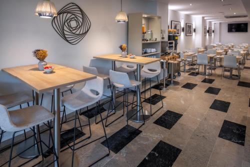 a restaurant with tables and stools in a room at Hotel SERHS Del Port in Barcelona
