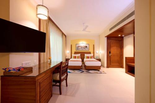 a hotel room with two beds and a flat screen tv at Sea Breeze Sarovar Portico Varca Goa in Varca