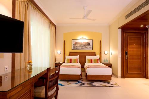 a hotel room with two beds and a flat screen tv at Sea Breeze Sarovar Portico Varca Goa in Varca