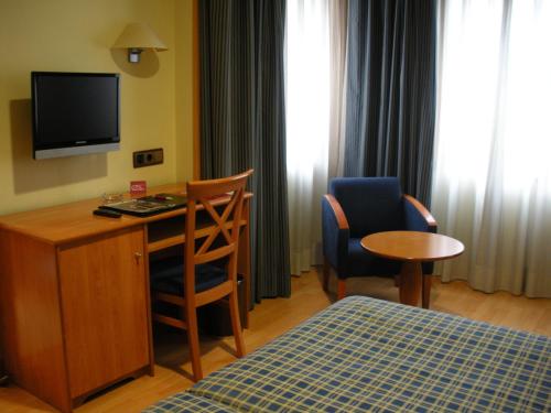 a hotel room with a desk and a bed and a television at II Castillas Madrid in Madrid