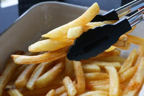 a knife and fork picking up a pile of french fries at The Riche Boutique Hotel Don Mueang Airport in Bangkok