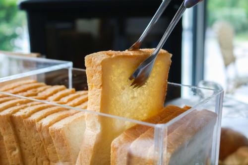a person cutting a piece of cake with a fork at The Riche Boutique Hotel Don Mueang Airport in Bangkok