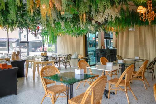 a restaurant with tables and chairs and plants hanging from the ceiling at The Riche Boutique Hotel Don Mueang Airport in Bangkok