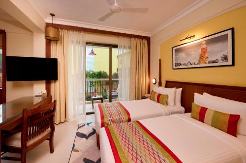 a hotel room with two beds and a television at Sea Breeze Sarovar Portico Varca Goa in Varca