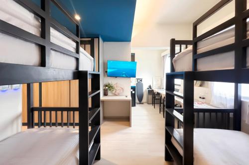 a dorm room with bunk beds and a desk at Coliwoo Hotel Pasir Panjang - CoLiving in Singapore