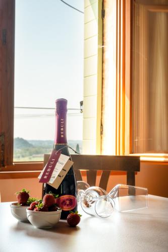 a bottle of wine and a bowl of strawberries on a table at Antica Rinaldo in Valdobbiadene
