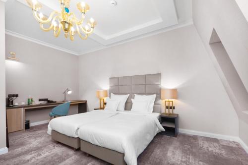 a bedroom with a large white bed and a chandelier at Grand Park Hotel in Szczecin