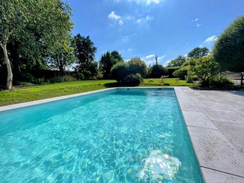 a swimming pool with blue water in a yard at La Chaumière Normande in Vattetot-sous-Beaumont