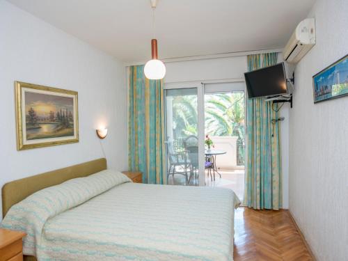 a bedroom with a bed and a television and a balcony at Apartments Dikan in Herceg-Novi