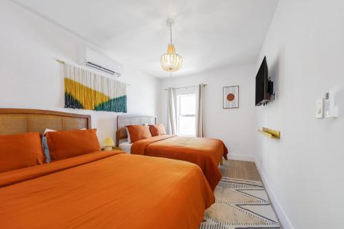 two beds in a room with white walls and orange sheets at Tropics Hotel Miami Beach in Miami Beach