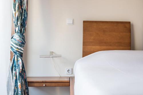a bedroom with a white bed and a wooden headboard at GuestReady - Back to Tullins in Leça da Palmeira