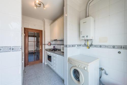 a white kitchen with a washing machine in it at GuestReady - Back to Tullins in Leça da Palmeira